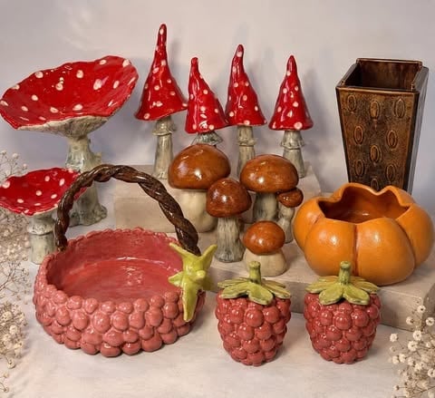 Dekoracyjne figurki grzybków i leśnych motywów: czerwone muchomory, brązowe pieczarki, dynie, ceramiczne jagody