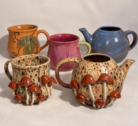 Kolekcja ceramicznych czajniczków i dzbanków z dekoracjami grzybowymi w ciepłych odcieniach